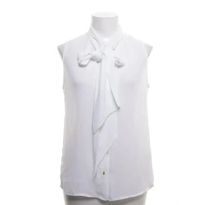 Vit ärmlös blus från Stockh LM - Elegant vit blus från Stockh LM med knytband vid halsen. Den är ärmlös och har en stilren design som passar perfekt för både vardag och fest. Blusen är tillverkad i ett lätt och luftigt material.