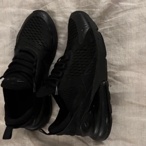 Svarta sneakers från Nike - Snygga svarta Nike sneakers med en modern design och bekväm passform. Skorna har snörning och en luftig ovandel som ger bra ventilation. Perfekta för både vardag och träning.