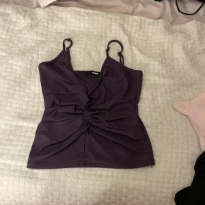 Lila ribbad linnetopp från Bik Bok - Snygg lila ribbad linnetopp från Bik Bok med justerbara axelband och en knutdetalj framtill. Perfekt för en stilren och bekväm look. Den är Urringad och helt ny aldrig använd.💞
