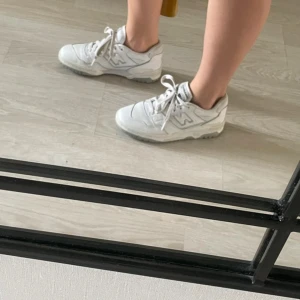 Vita sneakers från New Balance - Säljer ett par vita New Balance 550 sneakers med snörning. Skorna har en klassisk design med märkets logga på sidan, lite smutsiga men går att tvätta 