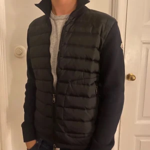 Svart pufferjacka från Moncler - Säljer en stilren svart pufferjacka från Moncler med dragkedja framtill. Jackan har långa ärmar och en quiltad design som ger extra värme. Perfekt för kyligare dagar och en snygg detalj i garderoben.