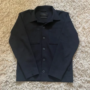 Overshirt från Zara - Snygg overshirt från Zara med knappar framtill och två bröstfickor. Perfekt för lager-på-lager stil. Skönt och stretchigt material i mycket fint skick. Knappt använd, storlek S. Nypris ca 800kr. Fraktarna antigen samma dag som köp eller dagen därpå💯