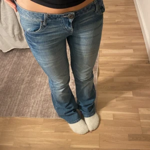 Blå bootcut jeans - Snygga blå bootcut jeans med låg midja. De har mönster av vitt broderi. Priset kan diskuteras💓storleken är 38/M men passar för storlek S också!!