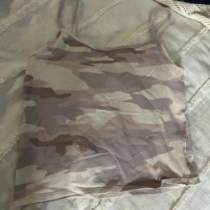 Camouflagefärgad linnetopp från American Eagle - Säljer en snygg camouflagefärgad linnetopp från American Eagle. Toppen har smala axelband och är perfekt för en avslappnad stil. Den är tillverkad i ett mjukt och bekvämt material.