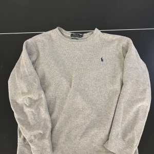 Grå tröja från Polo Ralph Lauren - Säljer en vintage grå tröja från Polo Ralph Lauren i storleken M. Tröjan är väl använd som är orsaken till prisen. Polos sidor säljer inte produkten något mera. Tveka inte att fråga flera frågor!