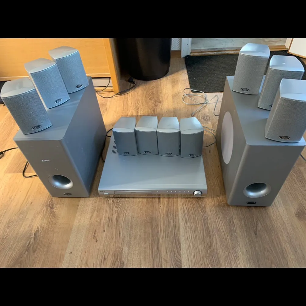 Säljer ett komplett hemmabiosystem med flera högtalare och två subwoofers i grått. Perfekt för att skapa en bioliknande ljudupplevelse hemma. Systemet inkluderar en central enhet och flera mindre högtalare för surroundljud.. Muu.
