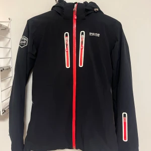 Skidjacka 8848 Altitude - Fodrad skidjacka från 8848 Altitude. Två bröstfickor, två fickor på magen, samt en ficka för liftkort. Har snölås och luva. Fint skick! Storlek 170 men fungerar som S också.