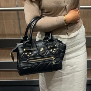 Svart quiltad handväska med dragkedja - Burberry handväska,  svart  med quiltad design och guldfärgade detaljer. Perfekt för att ge din outfit en elegant touch.