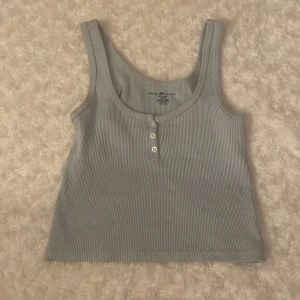 Ljusblå ribbad linnetopp från Brandy Melville - ljusblå ribbad linnetopp från Brandy Melville. Toppen har en rund halsringning och tre knappar framtill och är i bra skick❤️