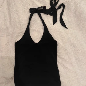 Svart topp - Snygg svart halterneck topp från Bik Bok med knytband i nacken. Perfekt för en stilren look. Toppen är ärmlös och har en djup urringning framtill. Skriv till mig gällande flera frågor❤️❤️