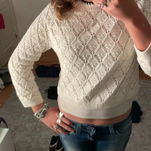 Vitt stickad tröja från Zara - Säljer en snygg beige stickad tröja från Zara med ett unikt mönster . Tröjan har långa ärmar och en rund halsringning med svart kant. 