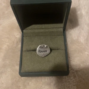 Maria Nilsdotter ring - Silvrig ring från Maria Nilsdotter som inte säljs längre, köpt för ca 3600 kr och är i jättebra skick!! Boxen med kommer ej tyvärr, minns inte vilken storlek det är men den är 2,3 cm i omkrets