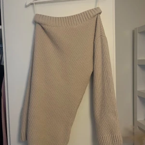 Beige stickad offshoulder klänning.  - Säljer en mysig beige stickad tröja med offshoulder-design. Perfekt för kyliga dagar med sin ribbade struktur och långa ärmar. En stilren och bekväm tröja som passar till många tillfällen.