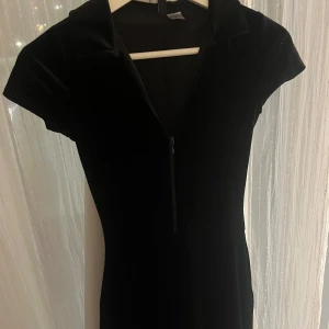 Svart elegant overall med dragkedja - Elegant svart overall i mjukt sammetstyg med korta ärmar och dragkedja framtill. Perfekt för en stilren look. Sitter väldigt fint. Den är xxs men jag hade xs när jag köpte den och den passade albsolut perfekt 