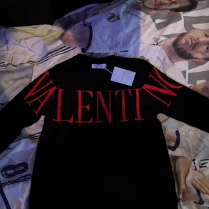 Svart tröja från Valentino - Snygg svart tröja från Valentino med röd text över bröstet. Tröjan har en rund halsringning och långa ärmar. Perfekt för en stilren look. Perfekt nu till vintern när det är kallt och när man vill ha en värmande tröja. Priset kan alltid diskuteras!!!