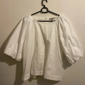 Vit blus från H&M - Säljer en stilren vit blus från H&M med vida trekvartsärmar och en rund halsringning. Passar bra till både jeans och kjol.