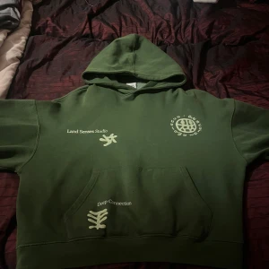 Grön hoodie från Zara - Säljer en grön hoodie från Zara med tryck både fram och bak. Hoodien har en stor ficka framtill och texten 'Land Senses Studio' och 'Deep Connection'.  10/10 condition