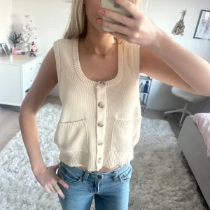 Beige stickad väst med knappar - Snygg beige stickad väst med knappar framtill och två fickor. Perfekt för lager-på-lager-stil och ger en mysig känsla. Använd en gång!💕
