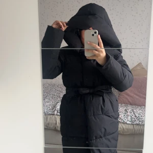 Svart dunjacka med bälte - Snygg och varm svart dunjacka med bälte i midjan som man kan knyta och ta bort, samt rymliga fickor. Använd 1 gång. Nypris 950kr. modellen på veromoda heter VmLeoniekate. Är 160. Jackan passar även en small. Jackan har även en dragkedja & knappar.