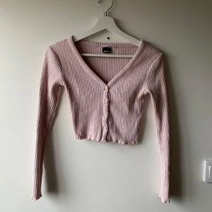 Rosa ribbad kofta från Gina Tricot - Säljer en söt rosa ribbad kofta från Gina Tricot. Den har en v-ringad design med knappar framtill och långa ärmar. Jag har sytt knapparna framtill men de går att sprätta upp om man skulle vilja ha knäppbara knappar isstllet.