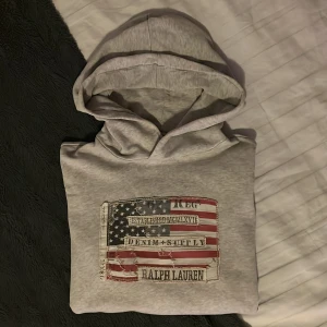 Ralph Lauren hoodie🇺🇸 - Säljer en grå hoodie från Ralph Lauren i storlek S. Den är i bra skick🇺🇸En hoodie som passar till de mesta. Hoodien har några väldigt små defekter (skickar bild vid behov). Några ”deffekter” är troligen en del av designen. Grejen är den att hoodien ska ha dedär ”slitna” utseendet, så det är svårt att urskilja defekterna från själva designen. Priset kan diskuteras. Hör av dig vid minsta fundering!