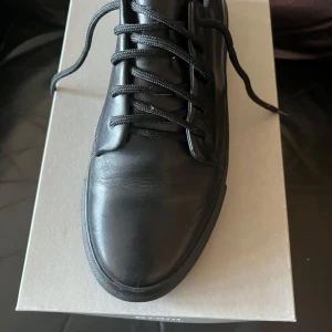 Svarta sneakers från Gram - Snygga svarta sneakers från Gram i skinn med klassisk snörning. Perfekta för en stilren look.