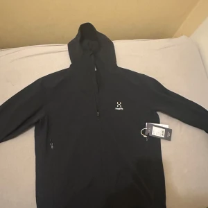 Svart hoodie från Haglöfs - Säljer en svart hoodie från Haglöfs i storlek XL. Den har en praktisk dragkedja och en bekväm huva. Perfekt för kyliga dagar och outdoor-äventyr.