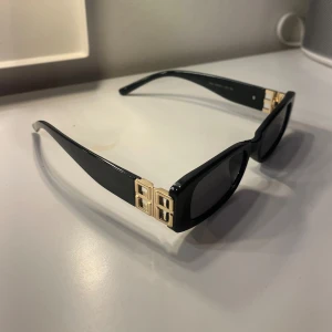 Svarta solglasögon med gulddetaljer - Snygga svarta solglasögon med rektangulära linser och gulddetaljer vid gångjärnen. Perfekta för en stilren look💖💖