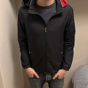 Svart vindjacka från Moncler - Säljer en svart vindjacka från Moncler. Jackan har dragkedja framtill och Moncler-logotypen broderad på ärmen. Perfekt för blåsiga dagar. Passar mig som är 174 och 9/10 skick