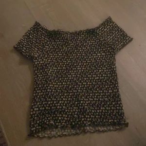 Blommig topp från Ü - Säljer en söt blommig topp från Ü i storlek 158/164. Toppen har korta ärmar och ett elastiskt material som ger en bekväm passform. Perfekt för en avslappnad stil.