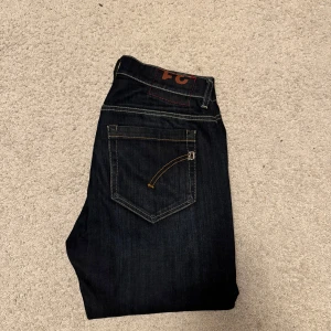 Dondup George  - Snygga mörkblå jeans från dondup med klassisk femficksdesign och är perfekta för en stilren look. Jeansen har en knappgylf och är tillverkade i ett slitstarkt material. Strl 31. Skicket är 9,5/10