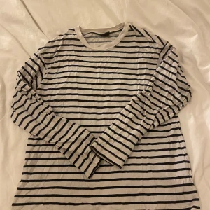 Randig långärmad tröja från Gina Tricot - Säljer en klassisk randig långärmad tröja från Gina Tricot i svart och vitt. Perfekt för en avslappnad stil. Tröjan är i storlek S och har en bekväm passform.