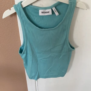 Turkos ribbad linnetopp från Weekday - Säljer en snygg turkos ribbad linnetopp från Weekday. Toppen är ärmlös och har en tight passform, perfekt för sommaren. Materialet är mjukt och stretchigt, vilket gör den bekväm att bära hela dagen. Passar bra till både jeans och kjol! köparen betalar för frakt 