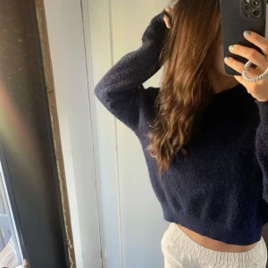 Mörkblå stickad tröja - Säljer en mörkblå stickad tröja. Har en normal passform, lite kortare i modellen, bra skick så den inte är för använd 