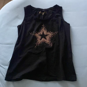 Svart linne  - Säljer ett svart oanvänt linne med en stjärna i mitten. Alla rhinestones är kvar💞 Använder INTE köp nu!!