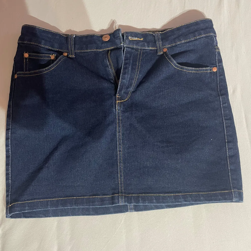 Säljer en snygg mörkblå jeanskjol från Perfect Jeans. Kjolen är i storlek S och har en klassisk femficksdesign med två bakfickor och tre framfickor. Den har en dragkedja och knapp framtill för enkel på- och avtagning. Perfekt för både vardag och fest!. Kjolar.