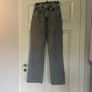 Gråa jeans med hög midja - Säljer ett par gråa jeans från bikbok med hög midja och rak passform. De är i storlek 28/32. en liten förslitning längst ner vid benlängden 