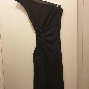 Jättefin oanvänd klänning med snygg öppning på sidan - Köpt på newyorker storlek s. Den har varit för liten för mig så har aldrig kommit till användning. Klänningen är offshoulder och följer kroppen jättefint. Finns ett snöre på sidan av klänningen där man kan justera längden och hur mycke öppet man vill