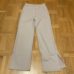 Beige ribbade byxor med slits - Säljer ett par snygga beige ribbade byxor. De är högmidjade och har en rak, vid passform. Byxorna har en liten slits vid bensluten som ger en extra touch. Perfekta för både vardag och fest! Använda ett par gånger och är i storlek S men passar också M. Köparen står för frakten 