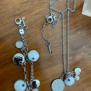 Fossil halsband och armband  - Jättefint halsband och armband från Fossil med söta berlocker och detaljer. Helt nytt. Längd på halsbandet: 35 cm Längd på armbandet: 23 cm