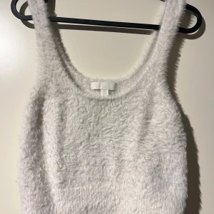 Vit fluffig linnetopp från H&M - Säljer en supermjuk och fluffig vit linnetopp från H&M. Perfekt för mysiga dagar eller som ett lager under en jacka. Toppen är ärmlös och har en skön passform. Passar perfekt till både vardag och fest!