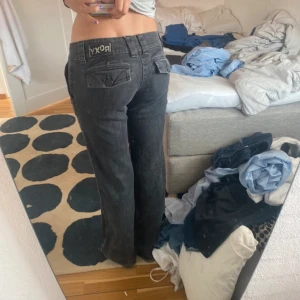 Svarta jeans från Roxy - Säljer ett par snygga svarta jeans från Roxy. De har en bootcut-stil och är lågmidjade, vilket ger en avslappnad och trendig look, dragkedjan ”pinne” har ramlat av men den fungerar fortfarande utmärkt!  midjemått 40cm rakt över