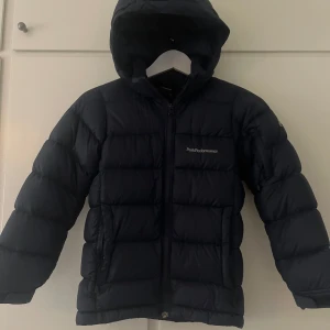 Peak performance vinterjacka  - En mörk blå peak performance jacka stl 140. Finns två små märken på ena armen. Annars fint skick. 