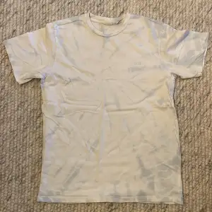 Säljer en snygg vit t-shirt från Levi's med tie-dye. Den är kortärmad och perfekt för en avslappnad stil. Levi's-loggan är diskret broderad på bröstet. Perfekt för sommardagar eller som en basplagg i garderoben!