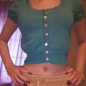 Turkos kortärmad kofta - Säljer en söt turkos kofta med korta ärmar och knappar framtill. Den är croppad och perfekt för sommardagar. Passar bra till både jeans och kjol!