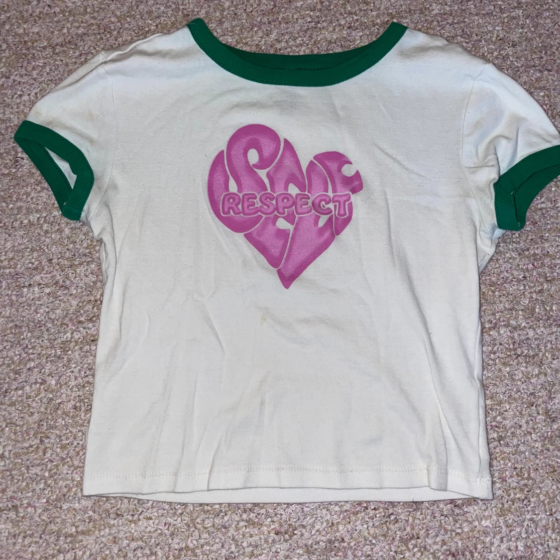 Vit T-shirt med gröna ”kanter” och rosa tryck.