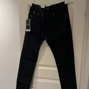 Säljer ett par svarta skinny jeans från Jack & Jones, modell Liam. De är lågmidjade och supertighta med en snygg passform. Perfekta för både vardag och fest! Helt nya med taggar kvar.