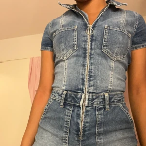 Jeansshorts med dragkedja - Säljer ett par snygga jeansshorts dress i blå denim med dragkedja framtill. De har en hög midja och är perfekt för sommarens alla äventyr. Shortsen har en tight passform och är i nyskick. 