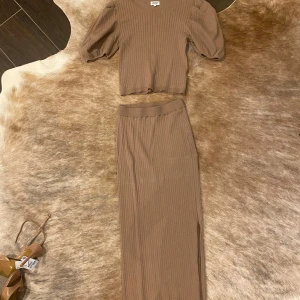 Beige ribbad topp - Säljer en superfin beige ribbad topp med trekvartsärm. Den är croppad och har en rund halsringning. Perfekt för både vardag och fest! ribbad kjol (sett) 