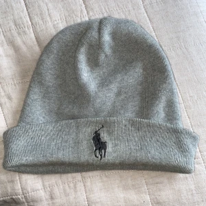 Polo Ralph Lauren Mössa - Grå Polo Ralph Lauren mössa i ljus grå.  Den är lite missfärgat på insidan och utsidan dock är det inte jätte synligt.